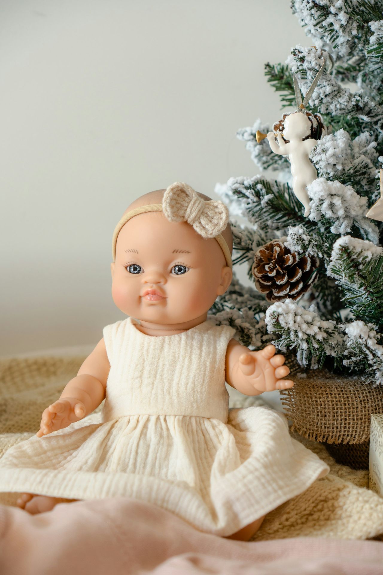 A baby doll sitting in front of a christmas tree